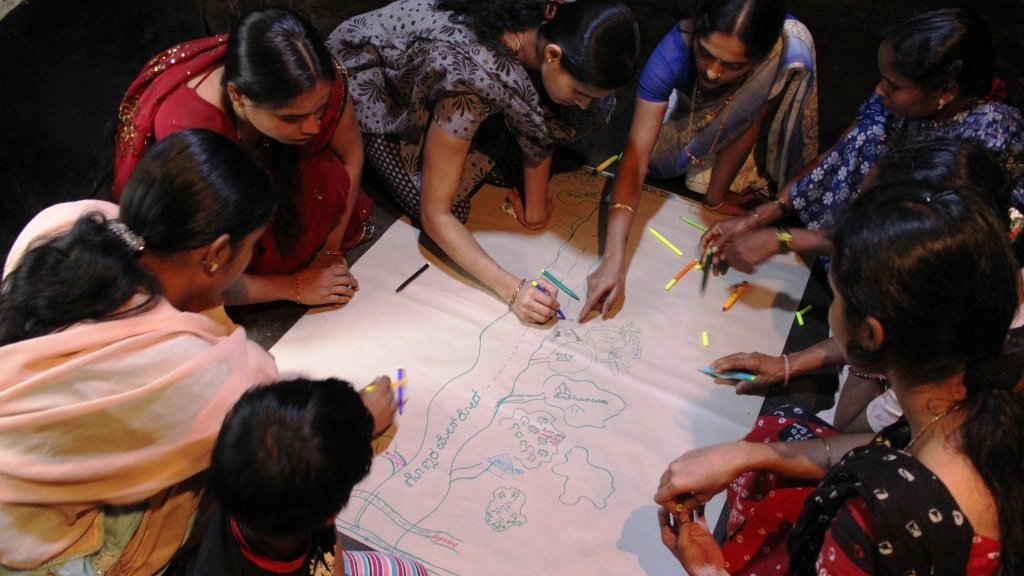 Women gather around to draw a community map.