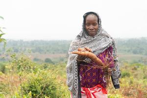 Zainabu, from Kisarawe district, Tanzania, holds cassava that she dug up on her hillside farm.